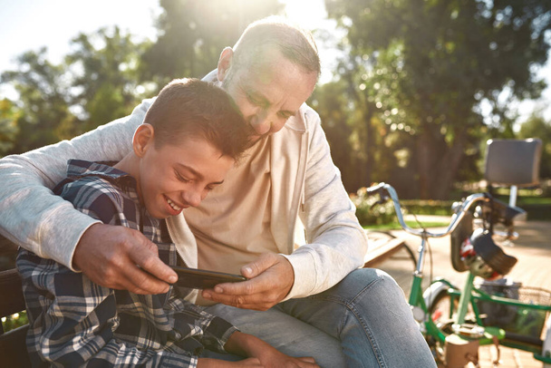 Father and son with cerebral palsy use smartphone - Photo, image