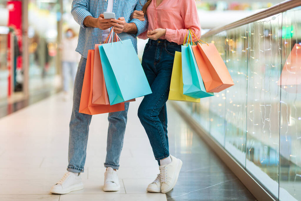 Nierozpoznanych małżonków robiących zakupy na stojąco Holding Shopper Bags In Mall - Zdjęcie, obraz