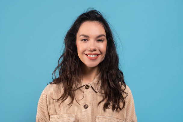 Smiling young european brunette woman in casual looking at camera isolated on blue background - Photo, image