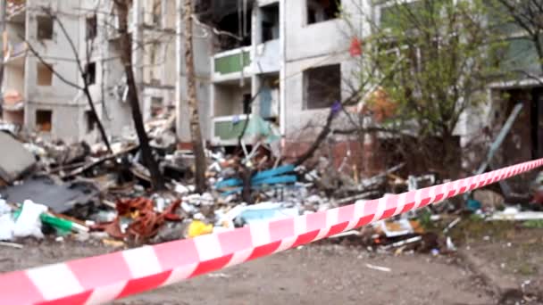 Encerrando el área de cinta de señal rojo-blanca cerca de un edificio residencial destruido después del bombardeo de la ciudad ucraniana por aviones rusos. Ruinas de la ciudad Chernihiv de ataques terroristas, bombardeos de bombas. - Imágenes, Vídeo