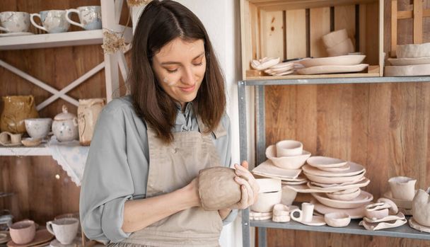 Portrait of a concentrated gochar woman, sculpting a clay bowl in a workshop. A young ceramist is engaged in pottery. - Foto, afbeelding