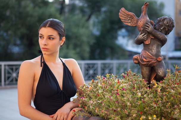Mladá sexy žena s černými šaty pózuje u fontány - Fotografie, Obrázek