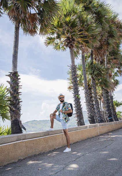 Young traveler man at summer holiday vacation with beautiful palms and seascapes at background - Foto, afbeelding
