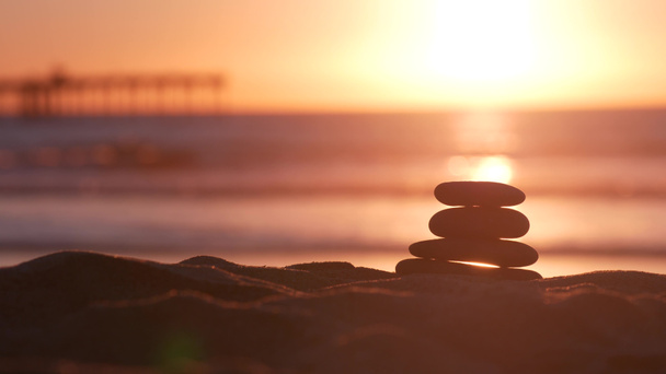 Stack of pebble stones, sandy ocean beach, sunset sky. Rock balancing by water. - Photo, Image