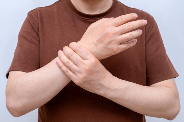 A man wrapped around his wrist because of wrist pain. Causes of rheumatoid arthritis, carpal tunnel syndrome, gout. Health care and medical concept. - Photo, image
