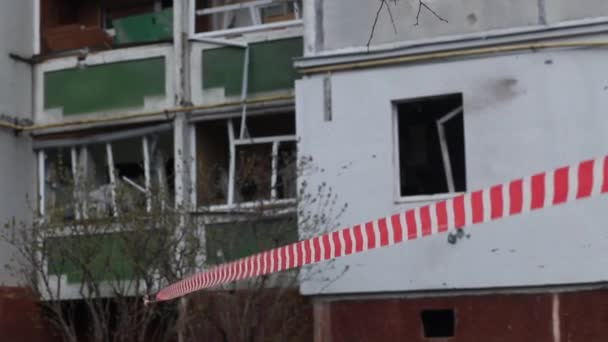 Fechando a área de fita de sinal vermelho-branco perto de um edifício residencial destruído após o bombardeio da cidade ucraniana por aeronaves russas. Guerra da Rússia contra a Ucrânia. - Filmagem, Vídeo