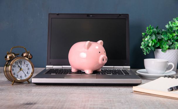 Piggy bank with laptop on table indoor - Фото, изображение