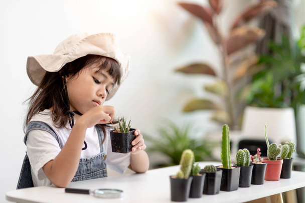 kid gently touch new stem of the cactus he grows with care, one hand holds magnifying glass.Nature education, Montessori and observation skills concept. - Fotografie, Obrázek