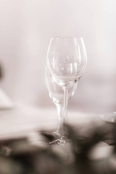 Empty glass set in restaurant. wedding, decor, celebration, holiday concept - romantic table setting with white tablecloth, plates, crystal glasses. - Photo, Image