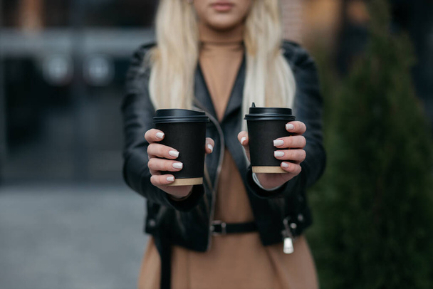 Paper cups in the hands of a girl. The girl squeezes the cups in her hands. Coffee. - Fotó, kép