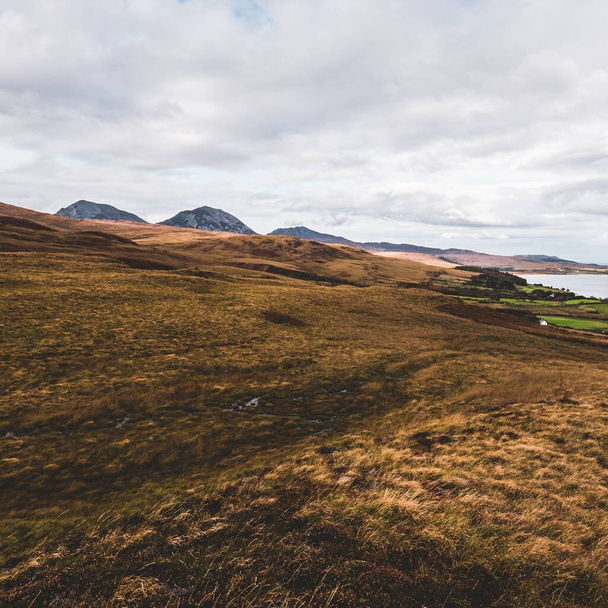 Panoramic aerial view of the shores, mountains and valleys of Jura island. Cloudy blue sky. Stormy weather. Paps of Jura, Inner Hebrides, Scotland, UK. Travel destinations, tourism, national landmarks - Photo, Image