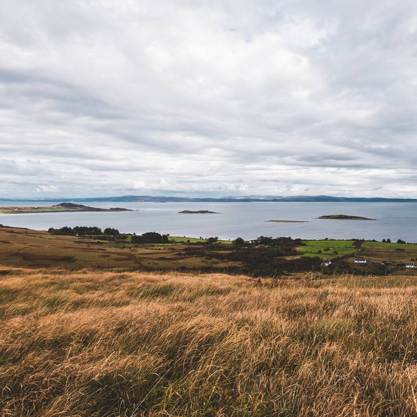 Panoramic aerial view of the shores, mountains and valleys of Jura island. Cloudy blue sky. Stormy weather. Paps of Jura, Inner Hebrides, Scotland, UK. Travel destinations, tourism, national landmarks - Photo, Image
