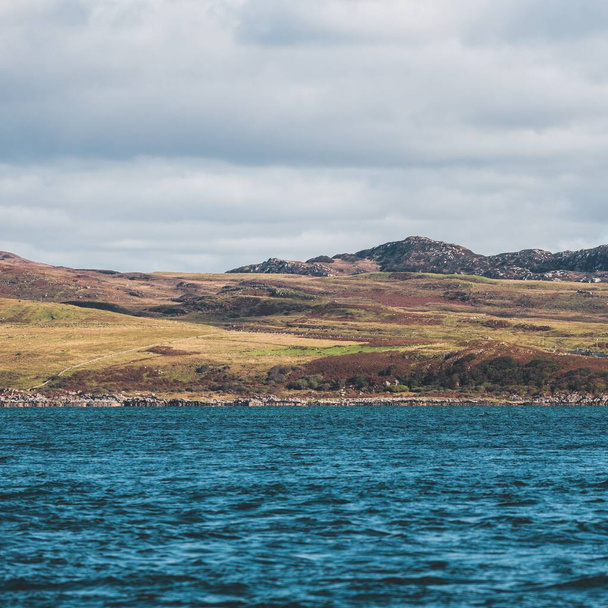Поблизу скелястих берегів (скель) західного узбережжя острова Юра видніється вид з яхти. Драматичне захід неба з яскравими хмарами. Внутрішній Гебрид, Шотландія, Велика Британія. Подорожні пункти, пам "ятки - Фото, зображення