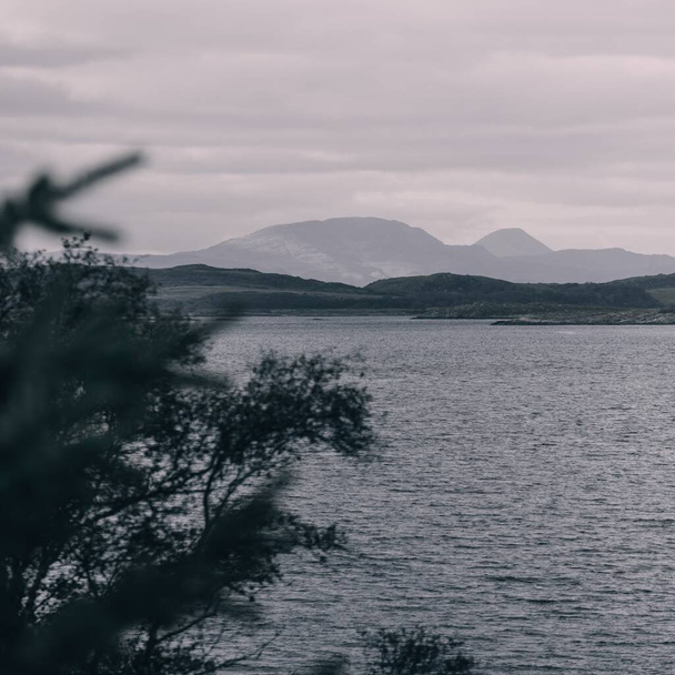 Panoramatický letecký výhled na skalnaté břehy, útesy, kopce, vrcholky hor a lesy poblíž Crinanu z vody. Argyll a Bute, Skotsko, Velká Británie. Dramatická oblačnost. Cestovní destinace, turistické téma - Fotografie, Obrázek