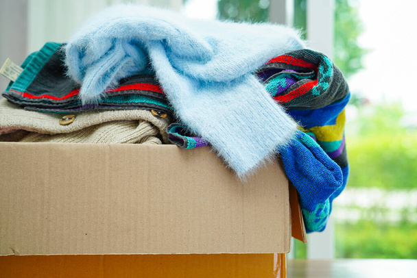 Clothes donations in cardboard box for volunteer. - Foto, Imagen