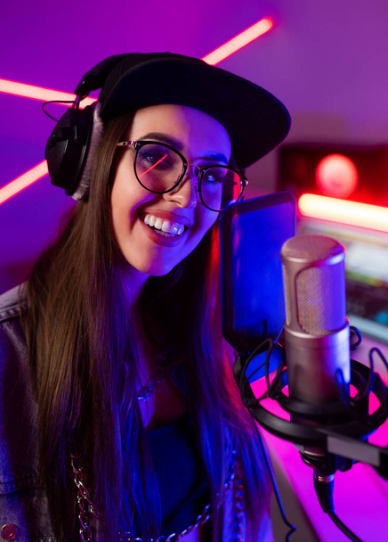 Piękna stylowa dziewczyna śpiewa do mikrofonu w studiu nagraniowym  - Zdjęcie, obraz