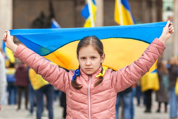 Verzamel steun Oekraïne. Oekraïense vlag in meisjes hand op Ondersteuning Oekraïense kinderen. Blijf bij Oekraïne. - Foto, afbeelding