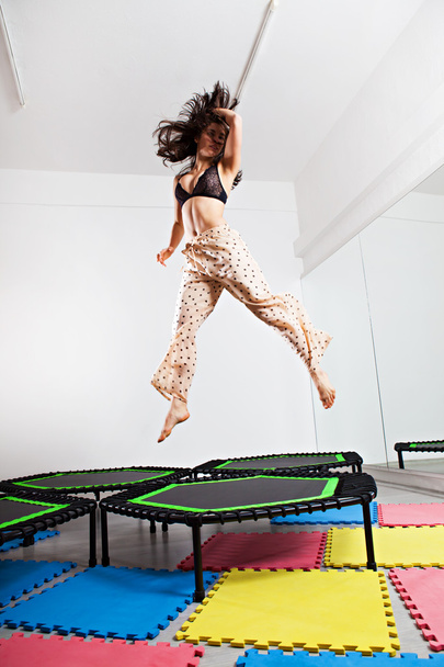 Femme brune sautante sur un trampoline
 - Photo, image