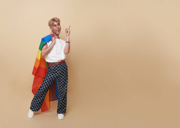 Молодий азіатський трансгендер ЛГБТ стоїть з пальцем, вказуючи ізольовані на оголеному кольоровому фоні з копіювальним простором
.  - Фото, зображення