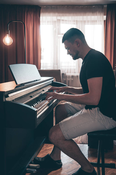 Músico masculino toca el piano electrónico en la habitación. - Foto, imagen