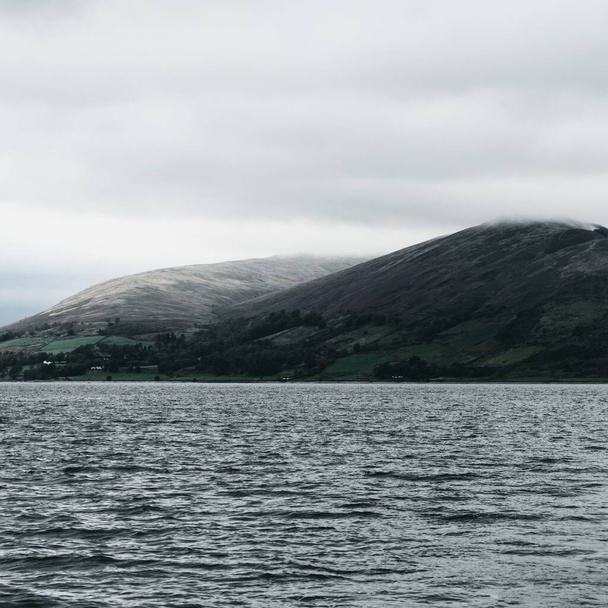 Zeilen in de buurt van de rotsachtige kusten van Kyles van Bute op een bewolkte dag. Schotland, Verenigd Koninkrijk. Dramatische stormachtige lucht. Reisbestemmingen, nationale bezienswaardigheden, toerisme, vakanties, recreatieve activiteiten - Foto, afbeelding