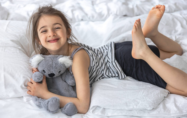 Felice bambina con morbido giocattolo koala a letto. - Foto, immagini