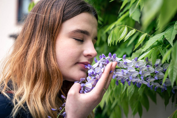 Młoda kobieta wyczuwa kwiat wisterii. - Zdjęcie, obraz