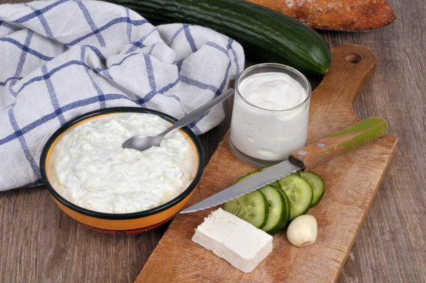 Ramekin of homemade tzatziki with its ingredients placed on a cutting board  - Photo, image