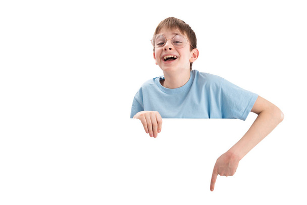 Happy smiling boy in large glasses points his finger down at empty space. Space for your text. Mockup. Isolated white banner. - Foto, imagen
