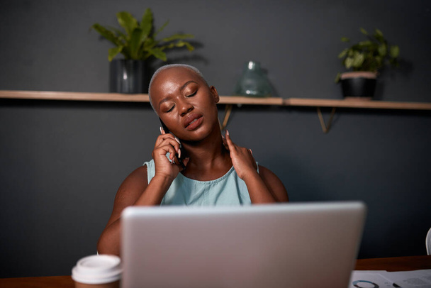 若い黒人女性がオフィスで夜遅くに電話を取り - 写真・画像