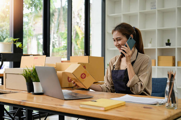 Startup SME small business entrepreneur SME or freelance Asian woman calling phone, online marketing packaging box and delivery, SME concept. - Foto, imagen