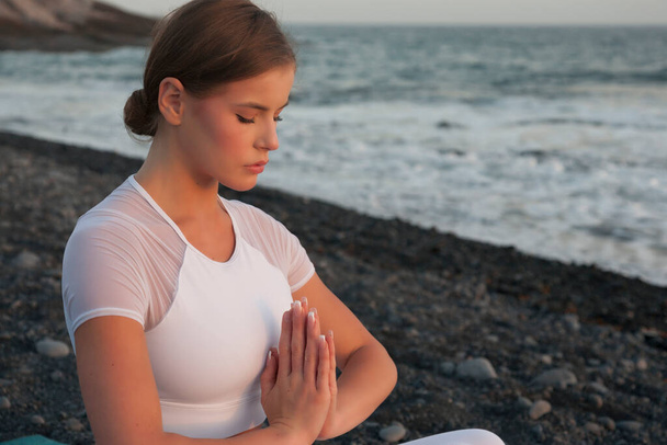 Young woman meditation in a yoga pose at the beach on sunset. Breathing practise. - 写真・画像