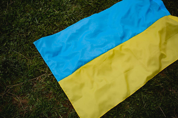 The Ukrainian flag lies on the grass. background. War in Ukraine. - Фото, изображение