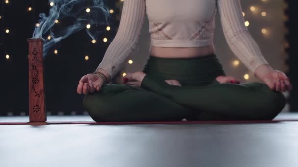 Smoldering wierook in de studio en vrouw mediteren op yoga mat - Video