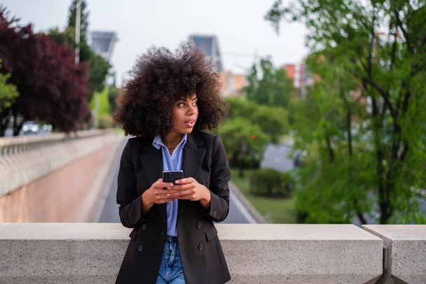 Молода жінка використовує свій смартфон на відкритому повітрі
 - Фото, зображення