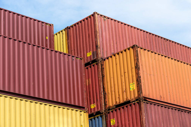 A stack of containers standing on top of each other in the loading yard by the wharf. - Zdjęcie, obraz