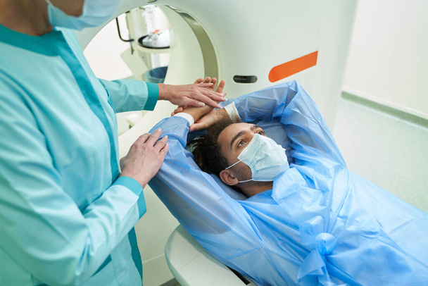 Female doctor helping male patient during MRI - Фото, зображення