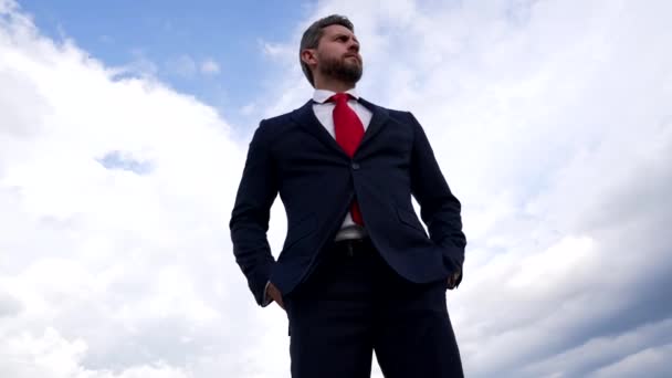 σοβαρός γενειοφόρος άντρας με επιχειρηματικό κοστούμι στο φόντο του ουρανού, επιχειρηματική μόδα - Πλάνα, βίντεο
