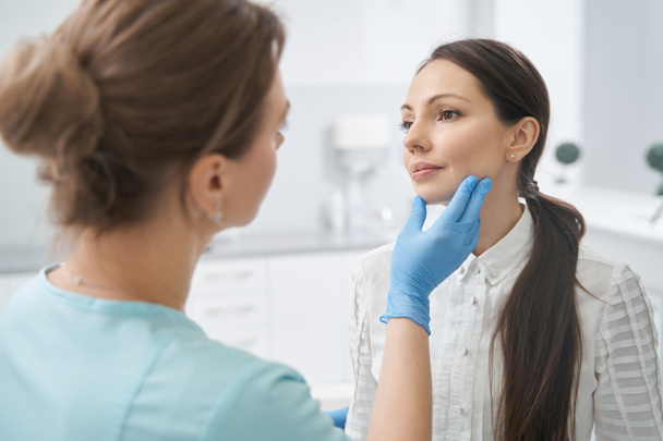 Esztétikai terapeuta ellenőrzi a nő arcbőrét a kozmetikai klinikán - Fotó, kép
