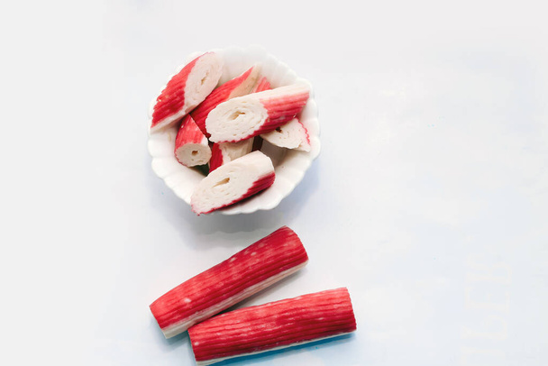 Sliced crab sticks in a cube for salad in a plate on a white table. - Foto, afbeelding