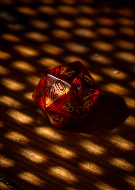 Vertical image of a red 20-sided role-playing die and pattern of light and shadow - Foto, immagini