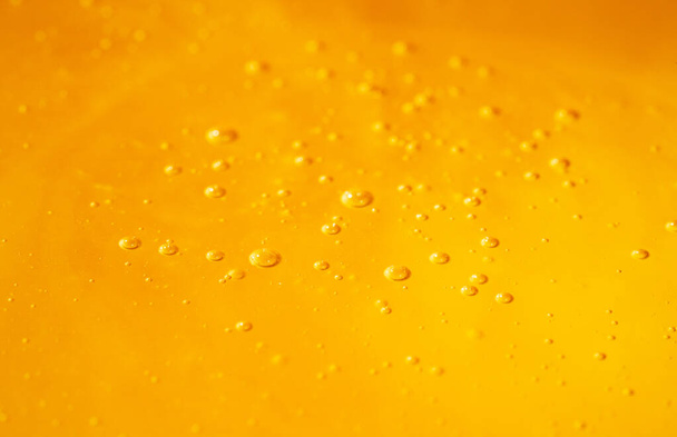Golden organic honey with bubbles. A splash with sweet syrup, molasses or yellow nectar. Close up of honey texture. Dessert, sweet food, bee product. - Photo, Image