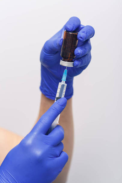 Пляшка вакцини ковід 19 і шприц в руці рукавички дослідника
 - Фото, зображення
