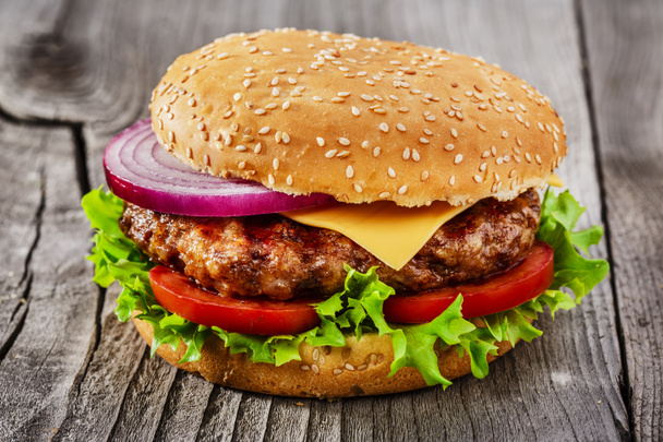 Hamburger mit gegrilltem Fleisch und Käse auf einer Holzoberfläche - Foto, Bild