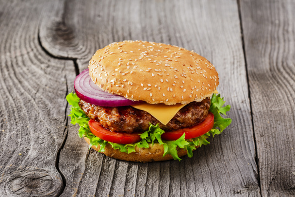 Hamburger with grilled meat and cheese on a wooden surface - Photo, Image