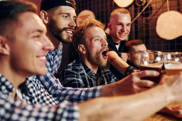 Fans cheer and shout. Group of people together indoors in the pub have fun at weekend time. - Fotoğraf, Görsel