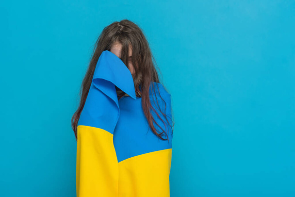Photo of a girl on a blue background. Yellow with blue fabric on the shoulders. - Фото, изображение