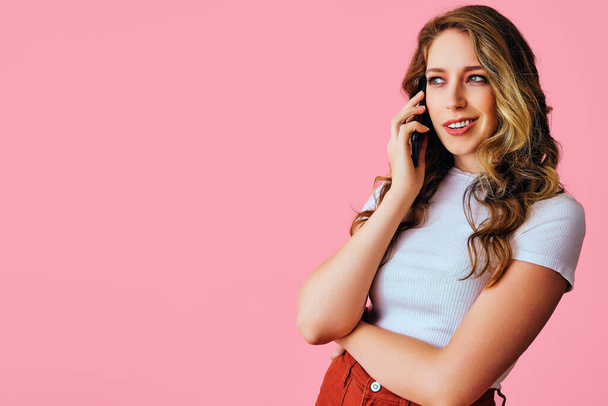 beautiful young woman talking on mobile phone isolated on pink - Фото, зображення