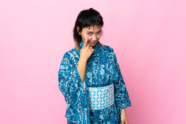 jonge vrouw dragen kimono over geïsoleerde blauwe achtergrond tonen iets - Foto, afbeelding