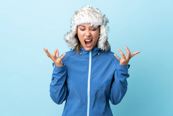 Young Uruguayan girl with winter hat isolated on blue background unhappy and frustrated with something - Φωτογραφία, εικόνα